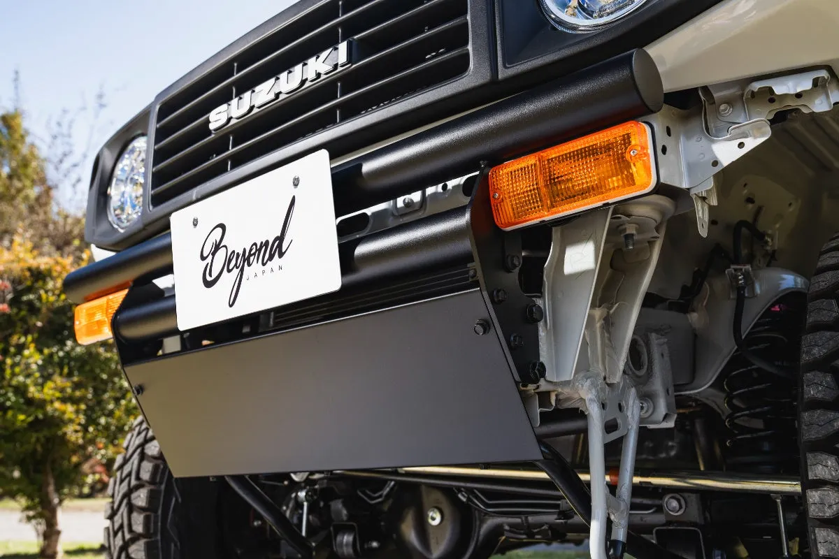 白いスズキジムニーのフロント部分の写真。ナンバープレートには「Beyond JAPAN」の文字、角型のオレンジ色のウィンカーが特徴的。
