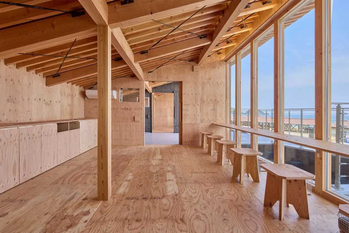 木材を基調とした内装の部屋。大きな窓から海が見え、カウンターとスツールが配置