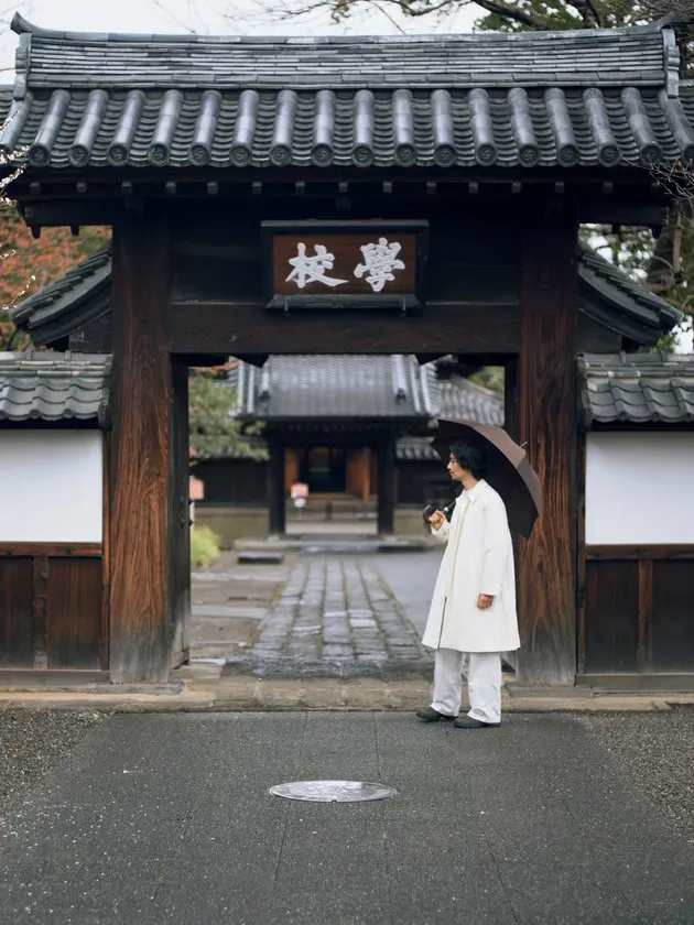 歴史ある建物の前に立つ斎藤工さん。現代と過去が静かに融合する瞬間。
