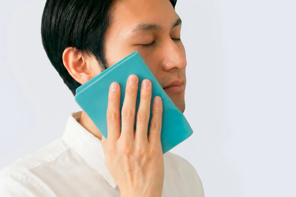 男性が青いタオルを顔に当てている様子